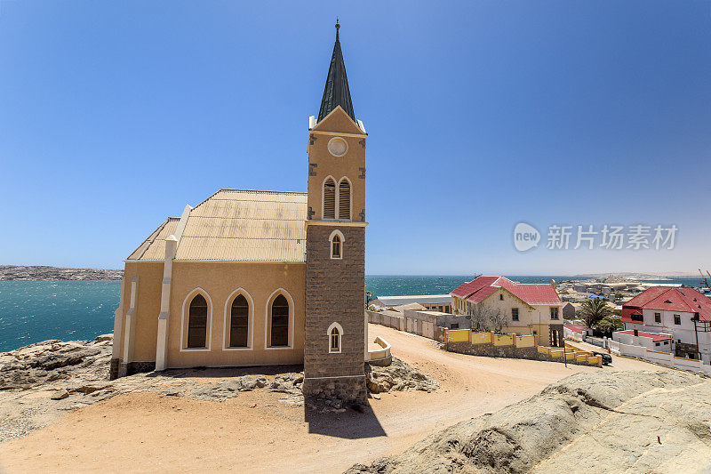 美丽的德国新教殖民教堂Felsenkirche全景，Lüderitz / Luderitz在纳米比亚，非洲。小镇的一部分作为背景。